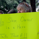 Cindy Beringer holds a sign as she watches a statue of Confederate President Jefferson Davis is moved from its location in front of the school’s main tower the University of Texas campus, Sunday, Aug. 30, 2015, in Austin, Texas.